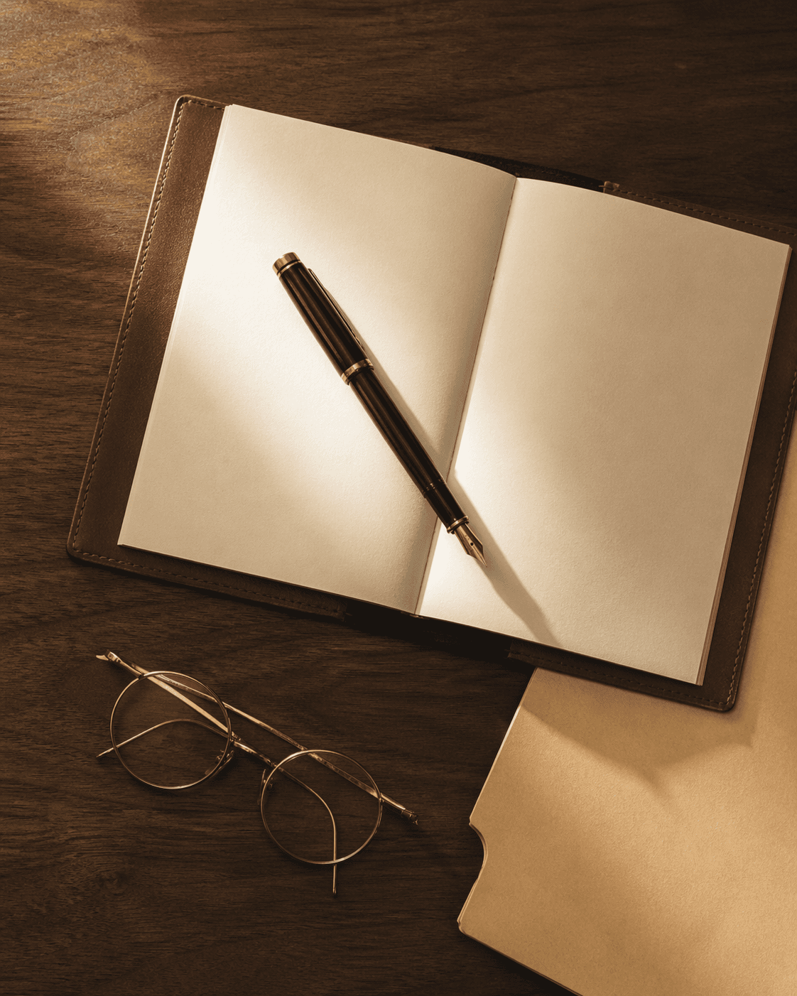 Editorial still life: fountain pen resting on an open leather notebook.